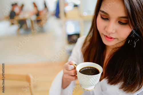 Portrait of beautiful woman holding a cup of coffee in her hand in blur background coffee shop, she drink coffee in the morning, vintage style