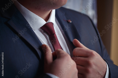 Φωτογραφία A man in a blue suit with a white shirt and maroon tie