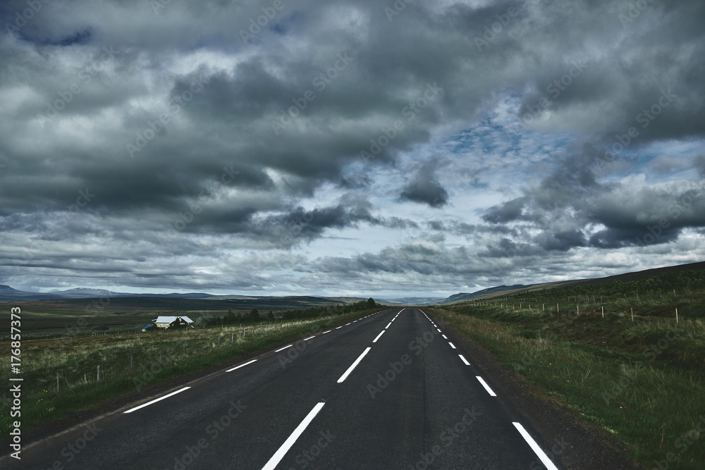 Travel to Iceland. plot of asphalt road in a dark cloudy mountain landscape. focus on the road