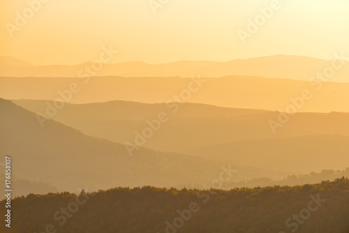 Golden shades on mountains at the horizon in the rays of sunlight at sunset