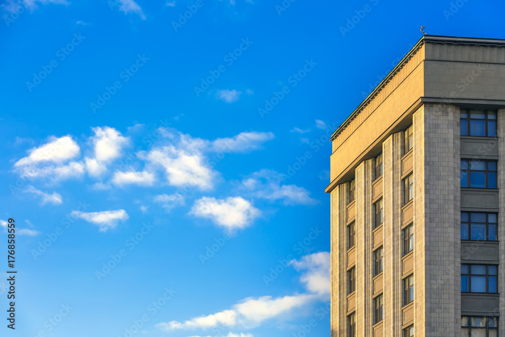 The building of classical architecture, strict and restrained, facing the walls with light limestone. A bright blue sky with small clouds. Copy space for text. Skyscraper, Moscow, Russia.