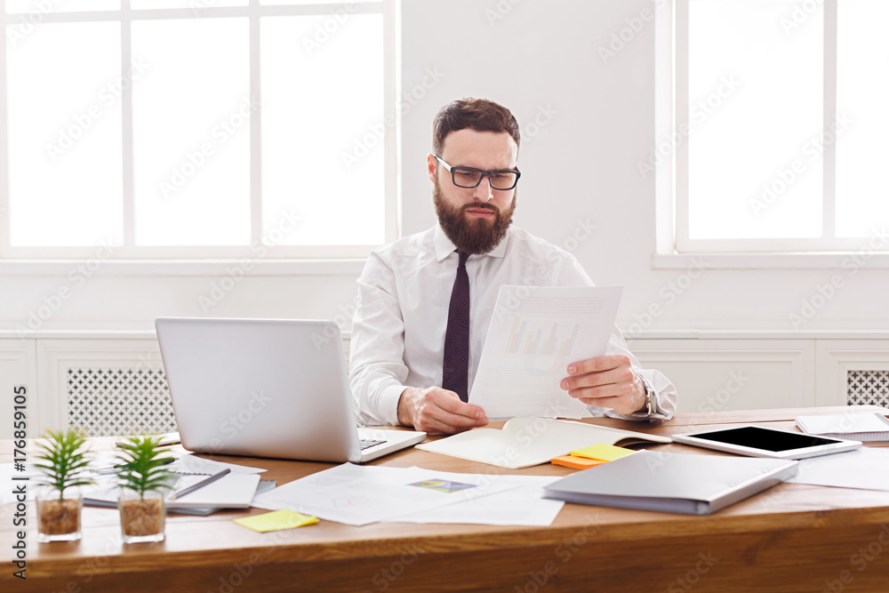 Concentrated businessman read documents in modern white office Concentrated businessman read documents in modern white office