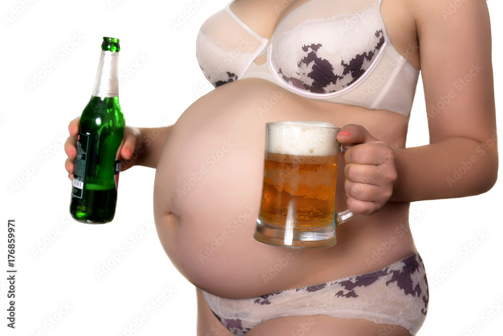 A pregnant woman alcoholic is addicted to alcoholic beverages. A girl in  the ninth month of pregnancy holds a mug and a bottle of beer. Stock Photo