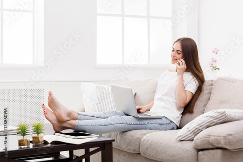 Pretty girl talking on mobile at home on the couch. Dark-haired girl in casual