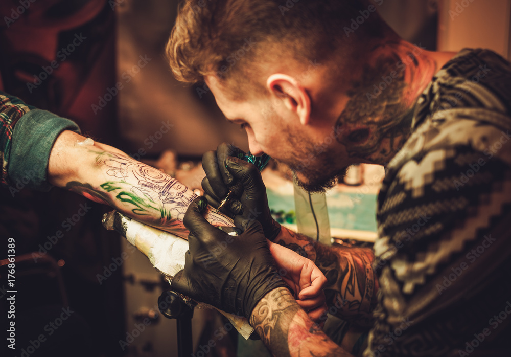 Obraz premium Tattoo artist makes a tattoo on a man's hand.