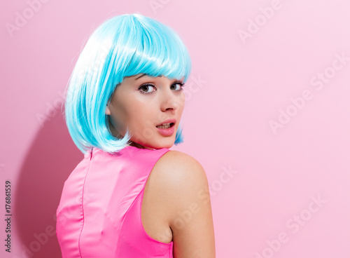 Beautiful woman in makeup with a bright blue wig on a pink background