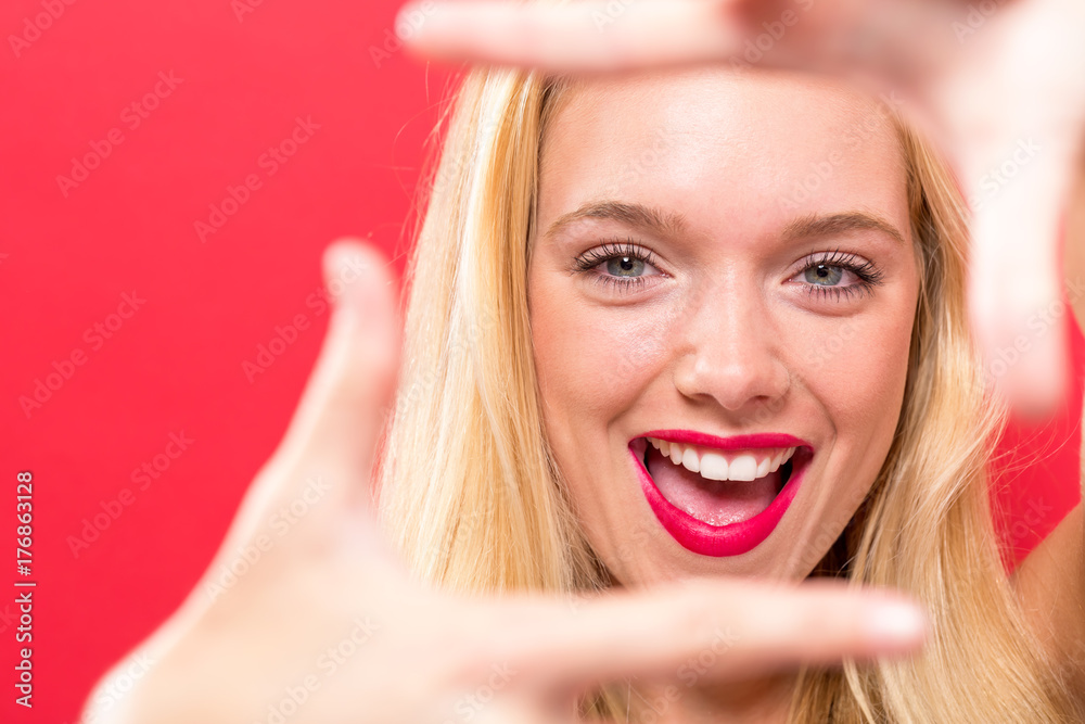 Naklejka premium Young woman framing her face with her fingers on a solid background