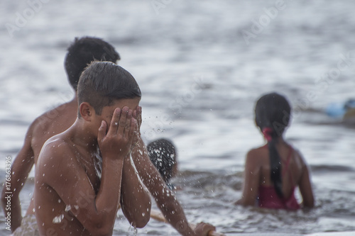 young man washing his face in the Ganges river enjoying a common day in community photo
