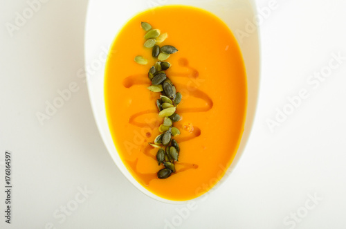 Pumpkin cream soup decorated pumpkin seeds in a bowl isolated on white background photo