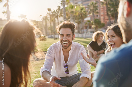 Young man sitting outside with friends laughing