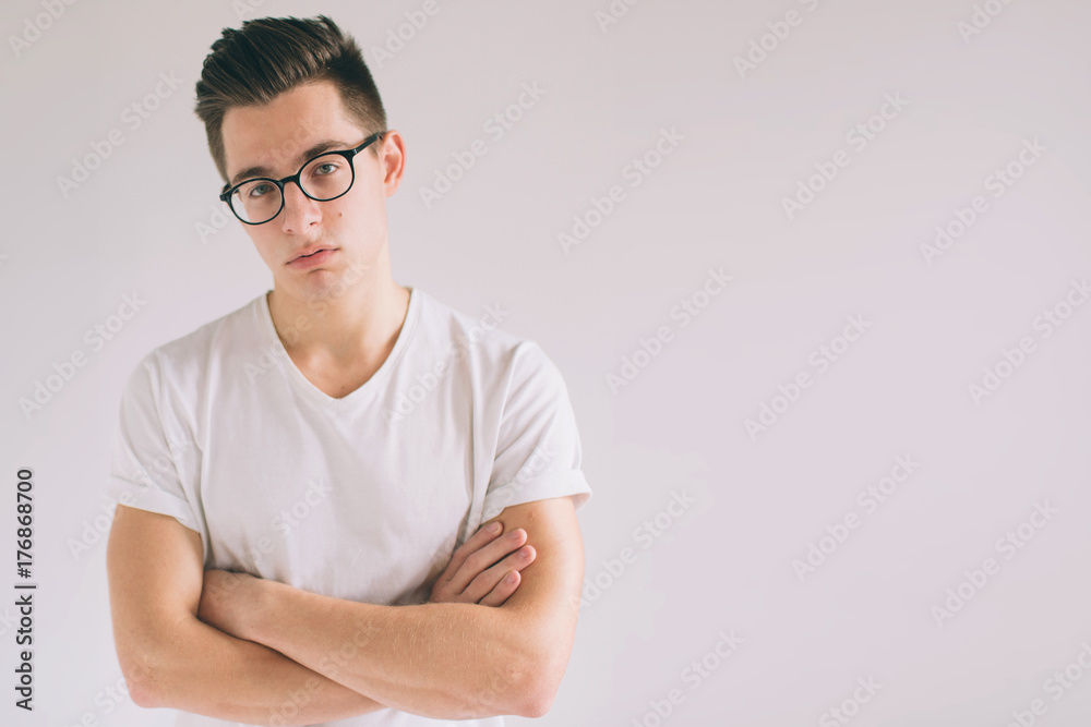 Unhappy student wearing casual t-shirt and glasses isolated on white. emotions and people concept.