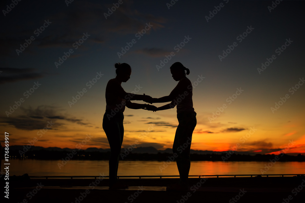 Silhouette young two women practicing yoga pose