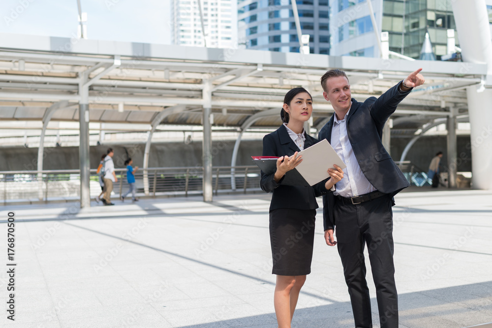 business man pointing his finger to building and talk about business plan with business woman at the city outdoor business man pointing his finger to building and talk about business plan with business woman at the city outdoor