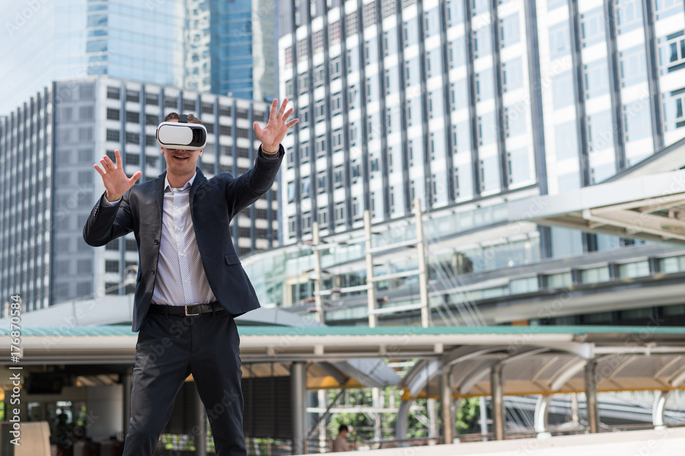 Caucasian Businessman wearing black suit and Virtual Reality Headset (VR) at the place outdoor and  building backgroud
