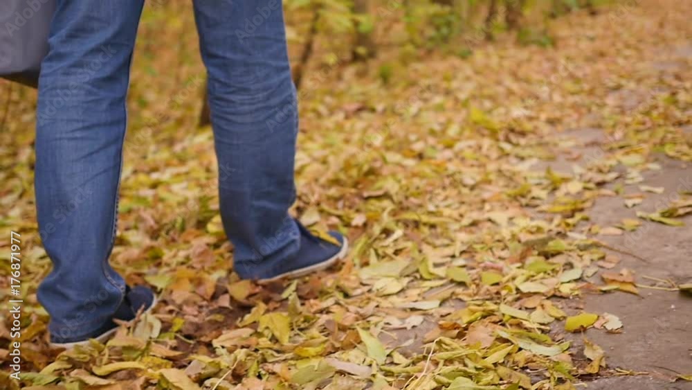 Boy walks in Autumn Park, yellow leaves lay underfoot. Sports outdoors.