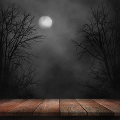 Old wood table and silhouette dead tree at night for Halloween background.