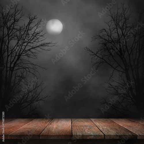 Old wood table and silhouette dead tree at night for Halloween background.