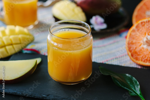 Orange and mango fruit juice over black slate.