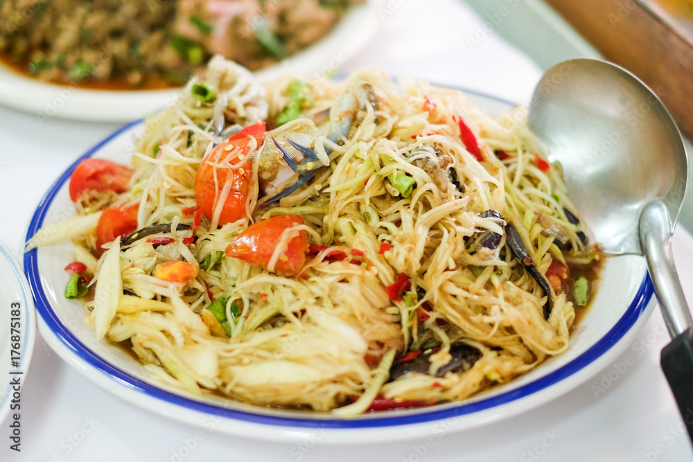 Som Tum Thai (Green Papaya Salad) with salted crab and tomato serve on white plate at Pattaya Thailand for food homemade background or texture. Som Tum Thai (Green Papaya Salad) with salted crab and tomato serve on white plate at Pattaya Thailand for food homemade background or texture.