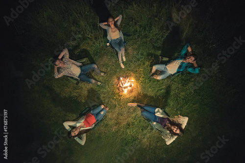The five happy people rest near the bonfire. view from above, evening night time