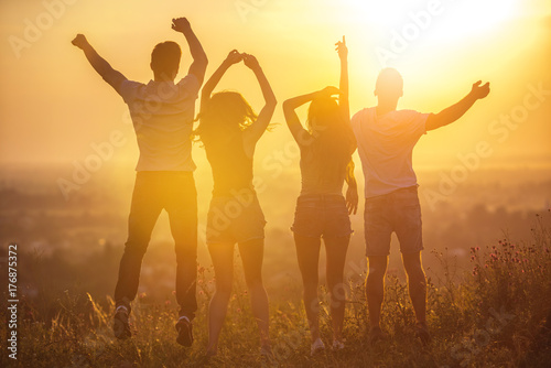 The four people jumping on the sunset background