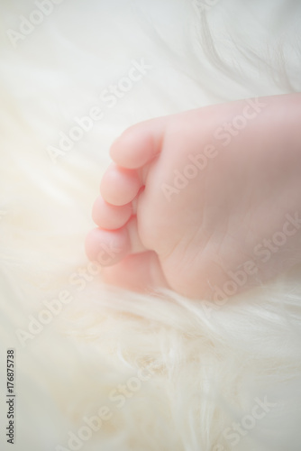 Bare feet of a cute newborn baby in warm white blanket. Childhood. Small bare feet of a little baby girl or boy. Sleeping newborn child.
