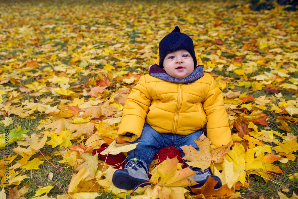child in a yellow jacket and scarf and hat sitting on the ground child in a yellow jacket and scarf and hat sitting on the ground