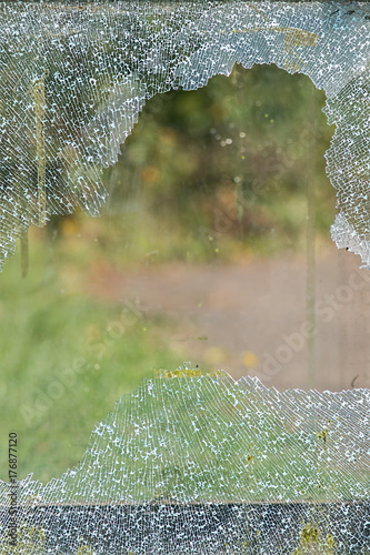 Smashed pane of broken window glass. Safety glass shattered by vandalism. photo