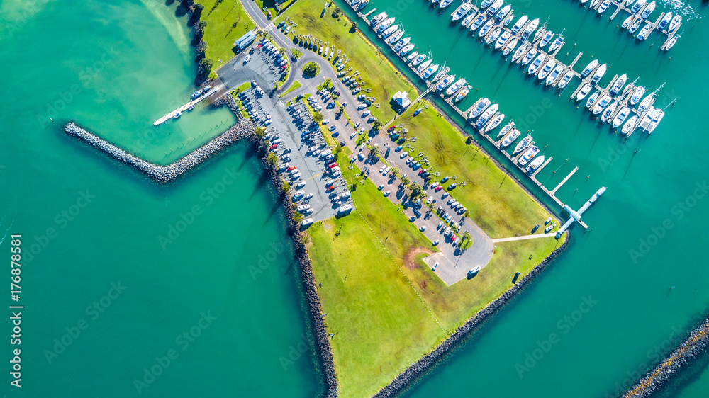 Aerial view on the entrance to the marina with boats resting along the pier and cars waiting on the parking space. Auckland, New Zealand