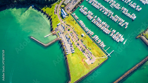 Aerial view on the entrance to the marina with boats resting along the pier and cars waiting on the parking space. Auckland, New Zealand photo