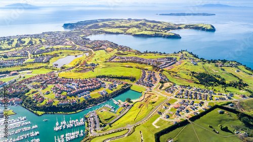 Aerial view on residential suburbs surrounded by sunny ocean harbour. Whangaparoa peninsula, Auckland, New Zealand photo