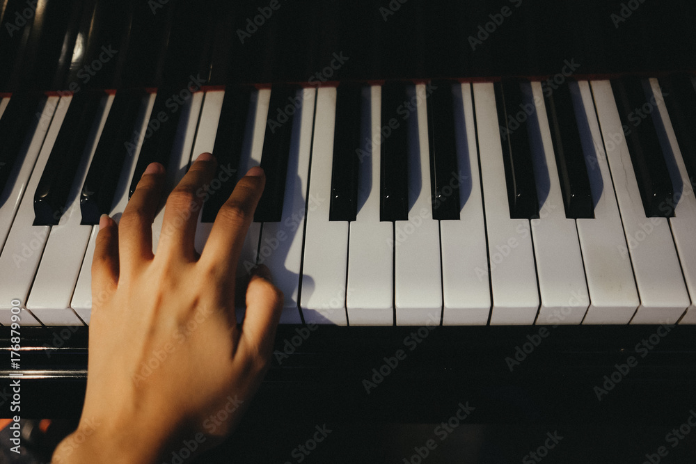 Obraz premium young woman use left hand play piano has piano key are background. this image for music, artist, art, instrument, entertainment concept