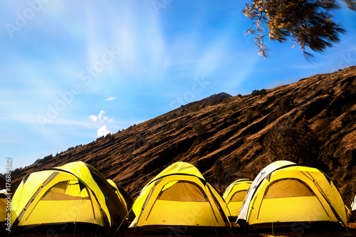 Campground in the mountains. Many yellow tents against the blue sky. photo