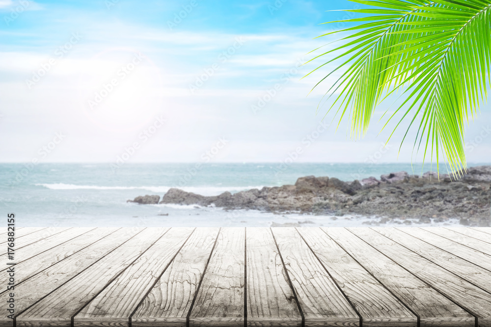 Fototapeta premium Empty wooden table and coconut leaves with party on beach blurred background in summer time.