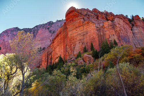 Trail view in Kolob Canyon part of Zion National Park in the autumn with the sun peeking behind a cliff.