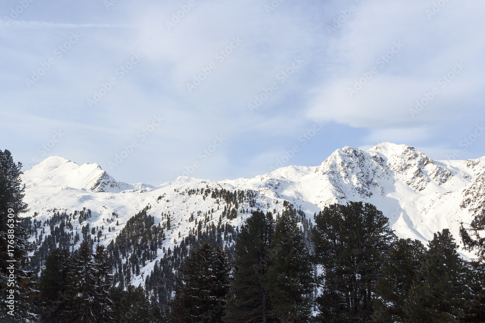Mountain panorama with snow, trees and blue sky in winter in Stubai Alps, Austria