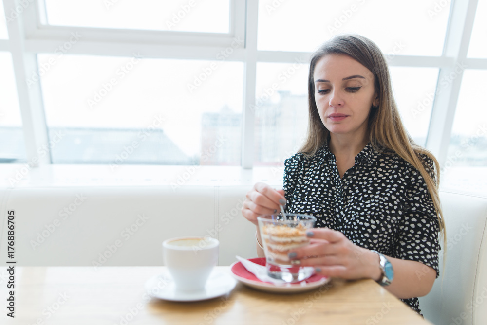 A beautiful woman eats a delicious dessert in a modern, stylish restaurant. Focus on the woman. A beautiful woman eats a delicious dessert in a modern, stylish restaurant. Focus on the woman.