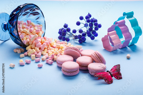 marshmallow and macaroons pouring out of jars. blue background. photo
