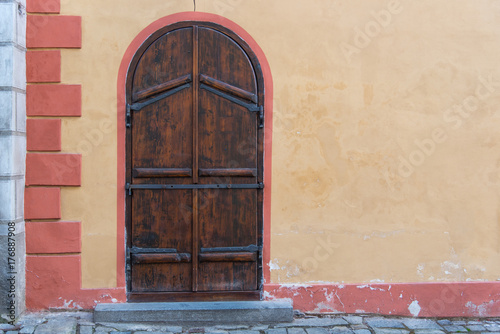 Arch old wooden door with rustic concrete yellow wall in Europe