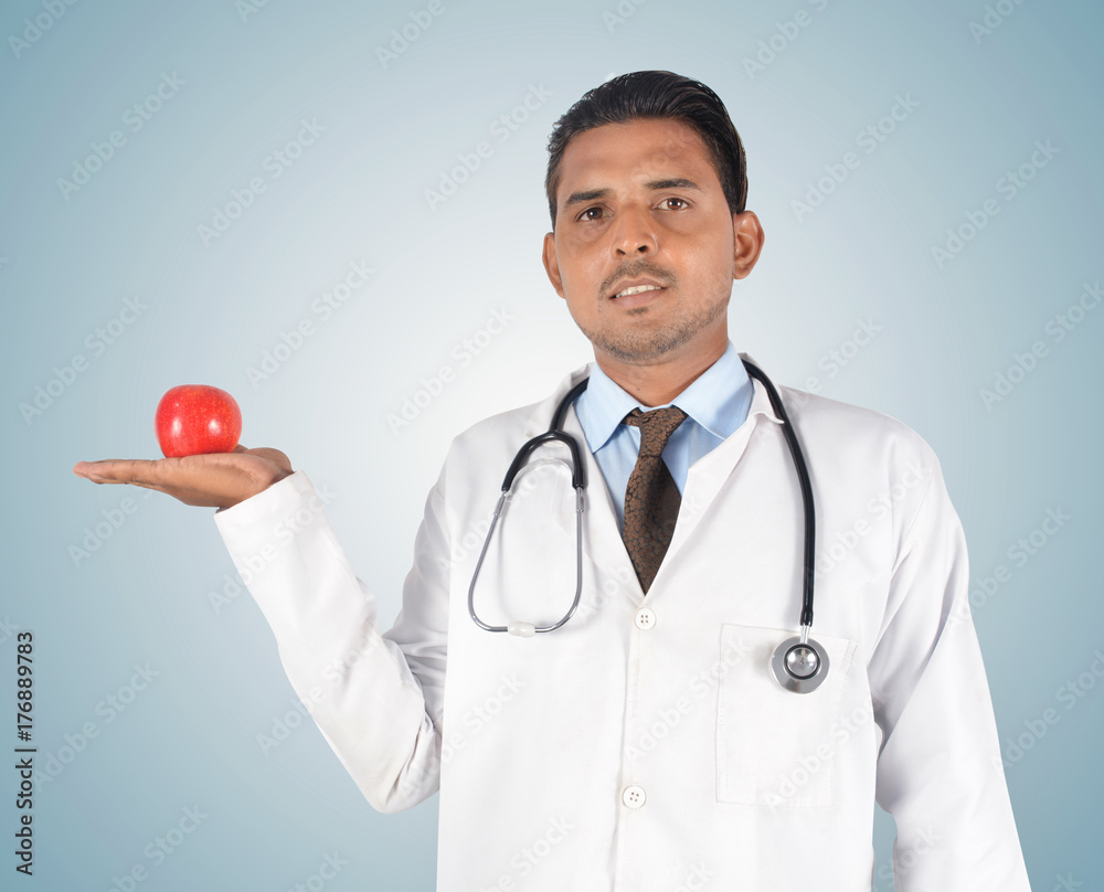 Young male doctor holding a red apple , health care idea Young male doctor holding a red apple , health care idea
