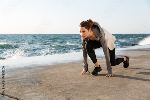 Photo of young brunette sport woman preparing to run, seaside outdoor