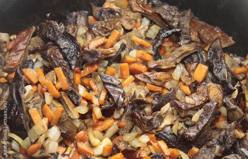 Mushrooms fried on the pan with carrot and onion