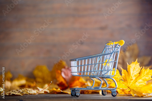 Vintage cart with maple tree leaves on yellow wooden background
