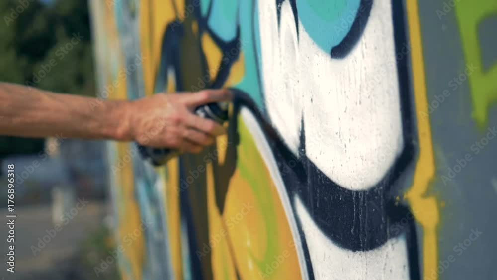 A hand makes black lines with graffiti paint.  