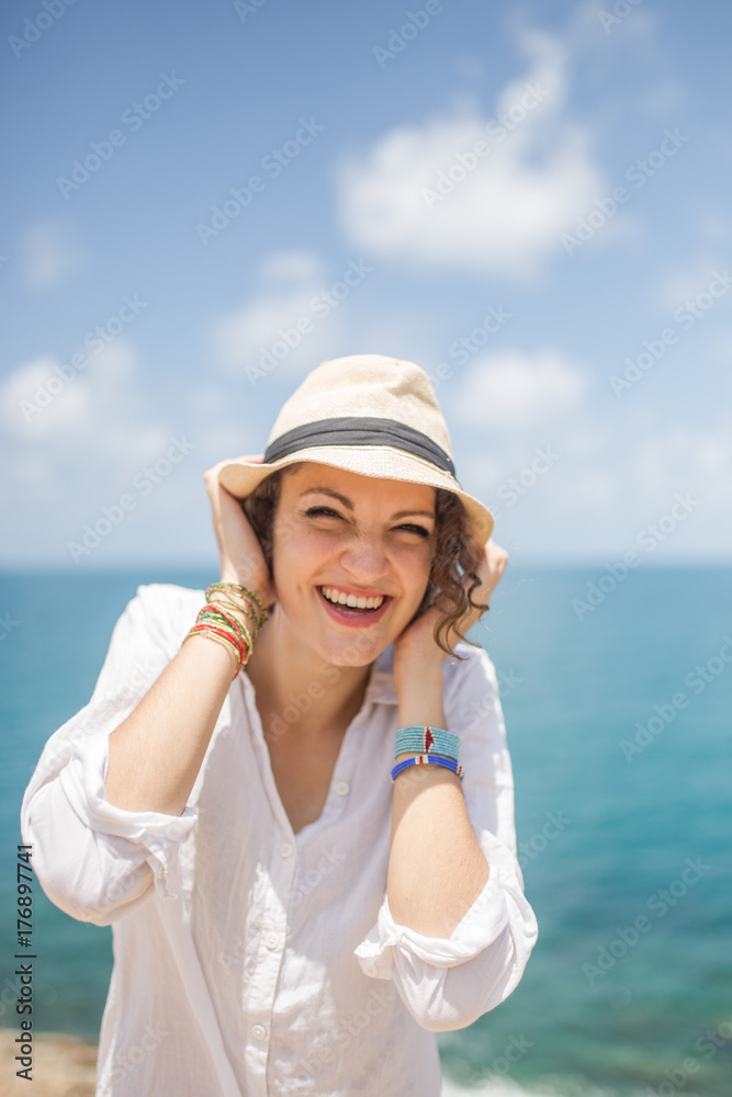 Portrait of a cute looking woman holding her hat on a windy day Portrait of a cute looking woman holding her hat on a windy day