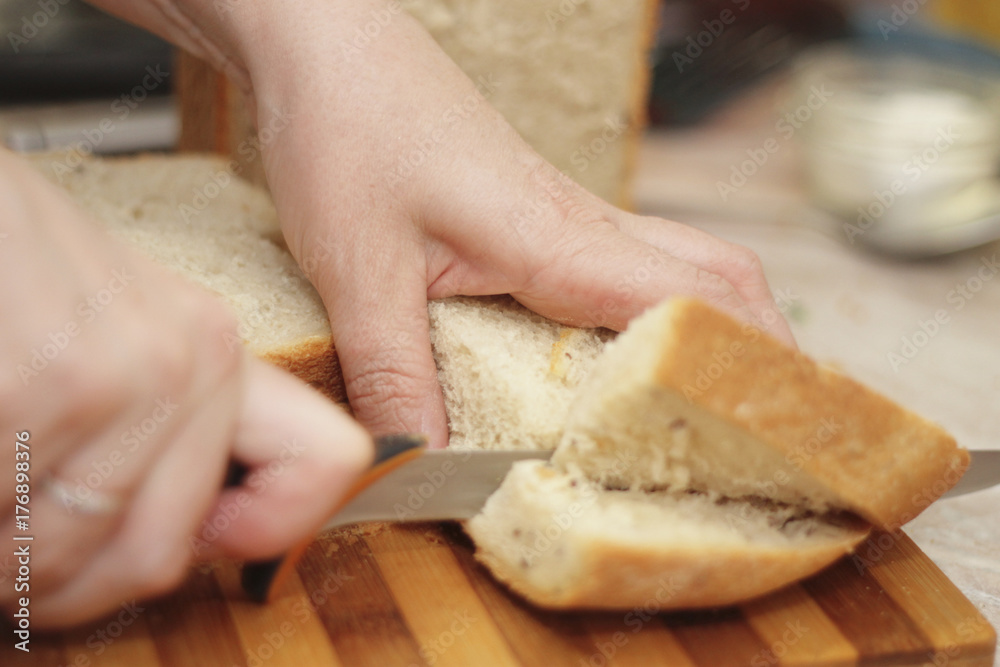 Woman cutting a bread on the wooden desk