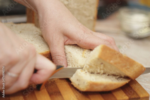 Woman cutting a bread on the wooden desk