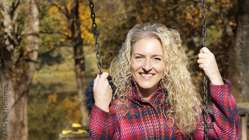 Young blond woman is having fun on the playground in autumn