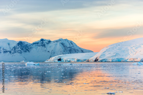 Sunset over idyllic lagoon with mountains and icebergs in the background at the Lemaire Strait, Antarctica