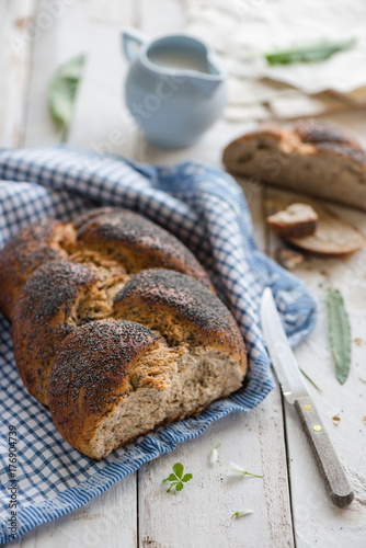 Plaited bread with poppy seed on a white table photo